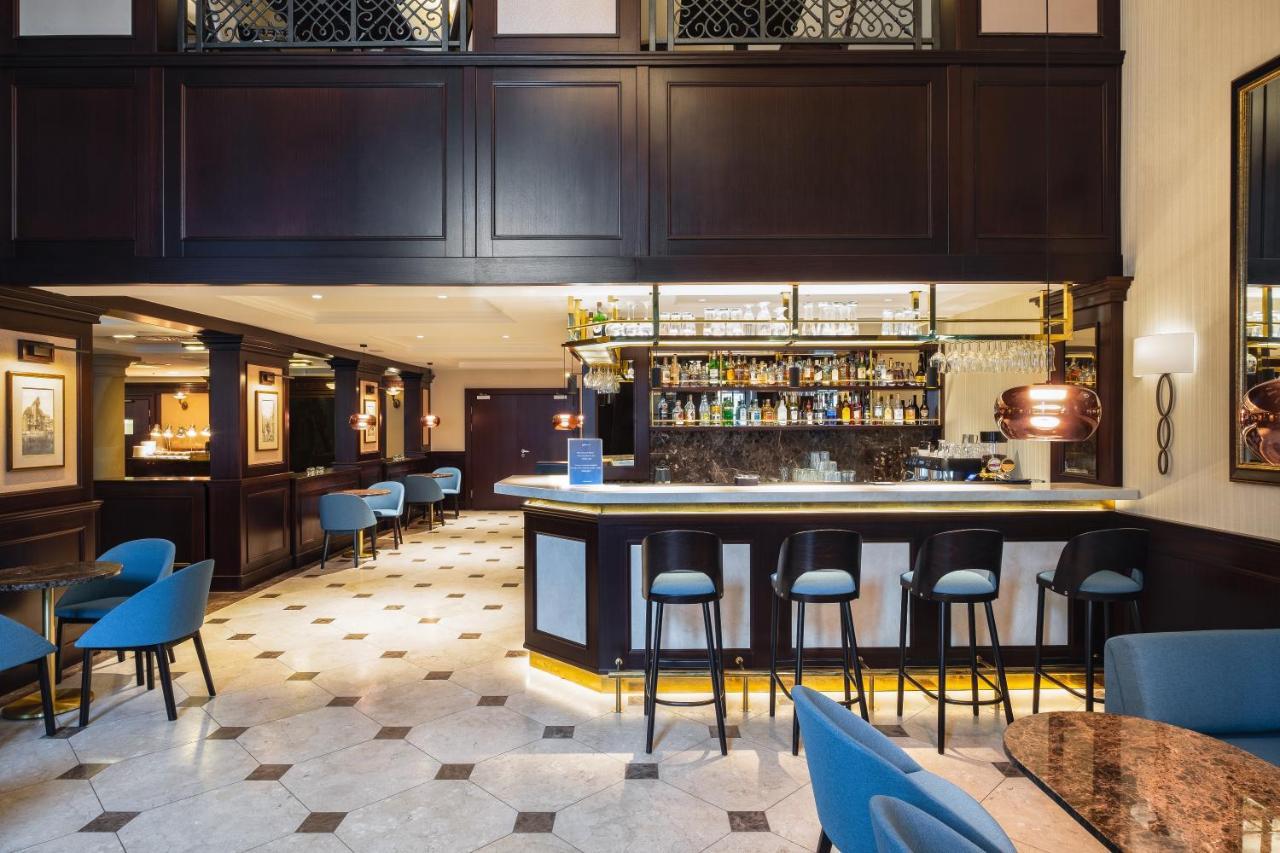 Radisson Blu Hotel, Danzica Esterno foto The photo shows the interior of a bar or restaurant. It features a sleek, modern design with dark wood paneling and elegant lighting. In the center, there is a well-lit bar with a variety of bottles displayed on shelves behind it. The bar has a curve