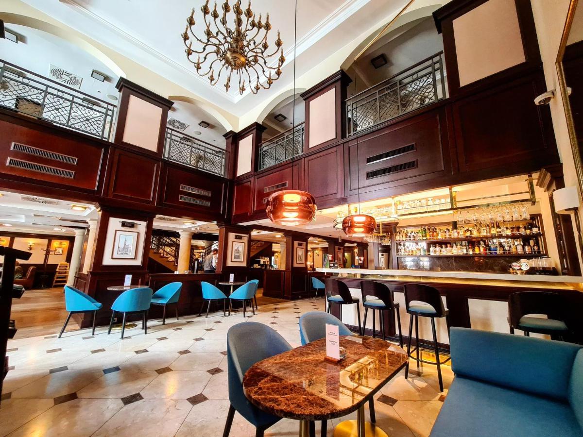 Radisson Blu Hotel, Danzica Esterno foto The photo depicts an elegant interior of a bar or restaurant. It features a high ceiling with a decorative chandelier and wooden paneling, creating a sophisticated atmosphere. The space is well-lit, with a long bar counter visible in the background, 