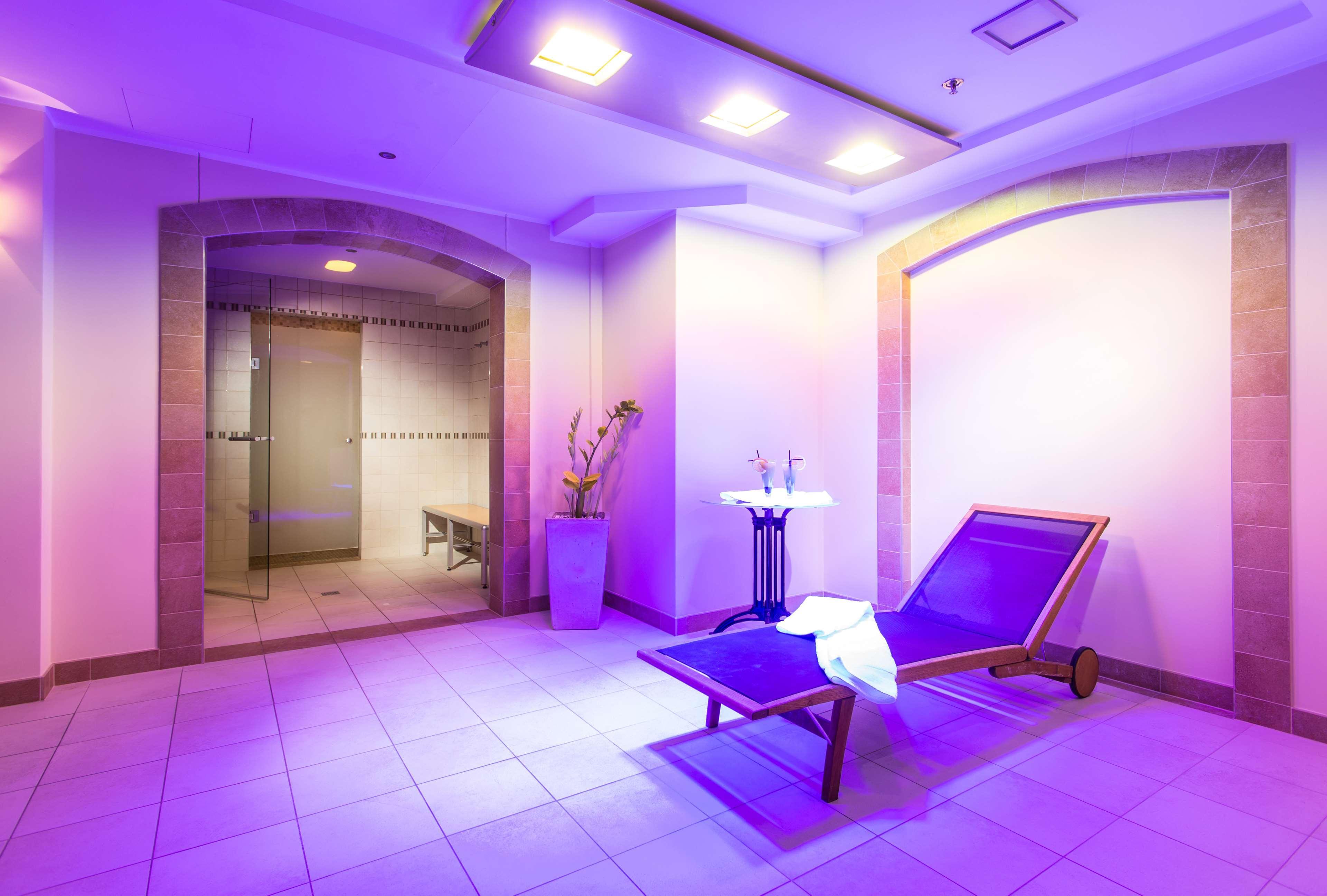 Radisson Blu Hotel, Danzica Esterno foto The photo shows a serene spa-like environment. There is a long, reclining lounge chair positioned in a softly lit area, with purple lighting creating a calming ambiance. Nearby, a small table holds two glasses, suggesting a place for relaxation. On t