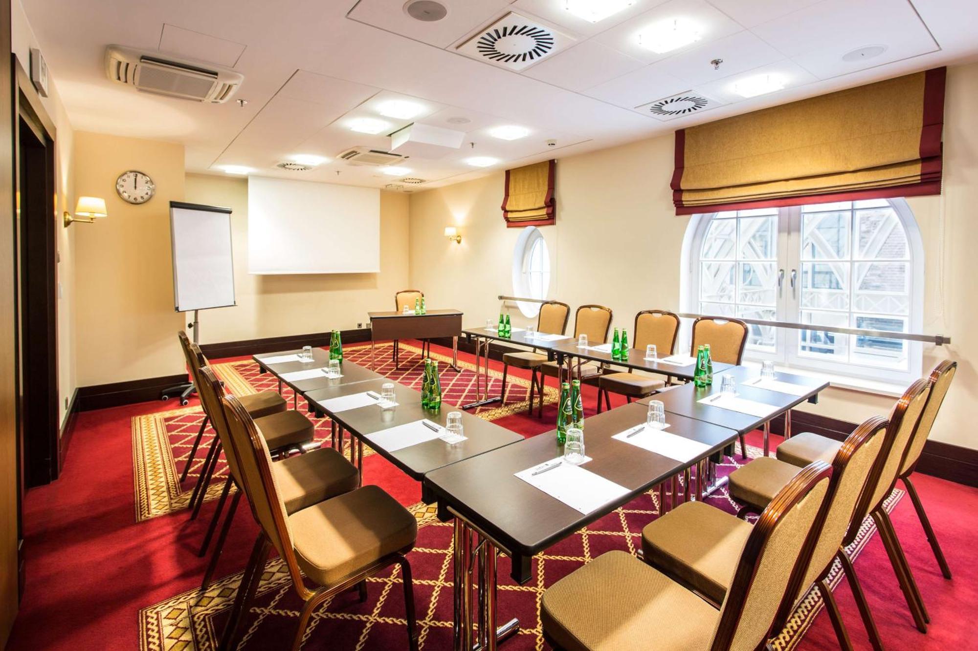 Radisson Blu Hotel, Danzica Esterno foto The photo shows a conference room set up for a meeting. It features a large rectangular table surrounded by several chairs. On the table, there are bottles of water and paper notepads for participants. A flip chart is positioned at one side of the ro