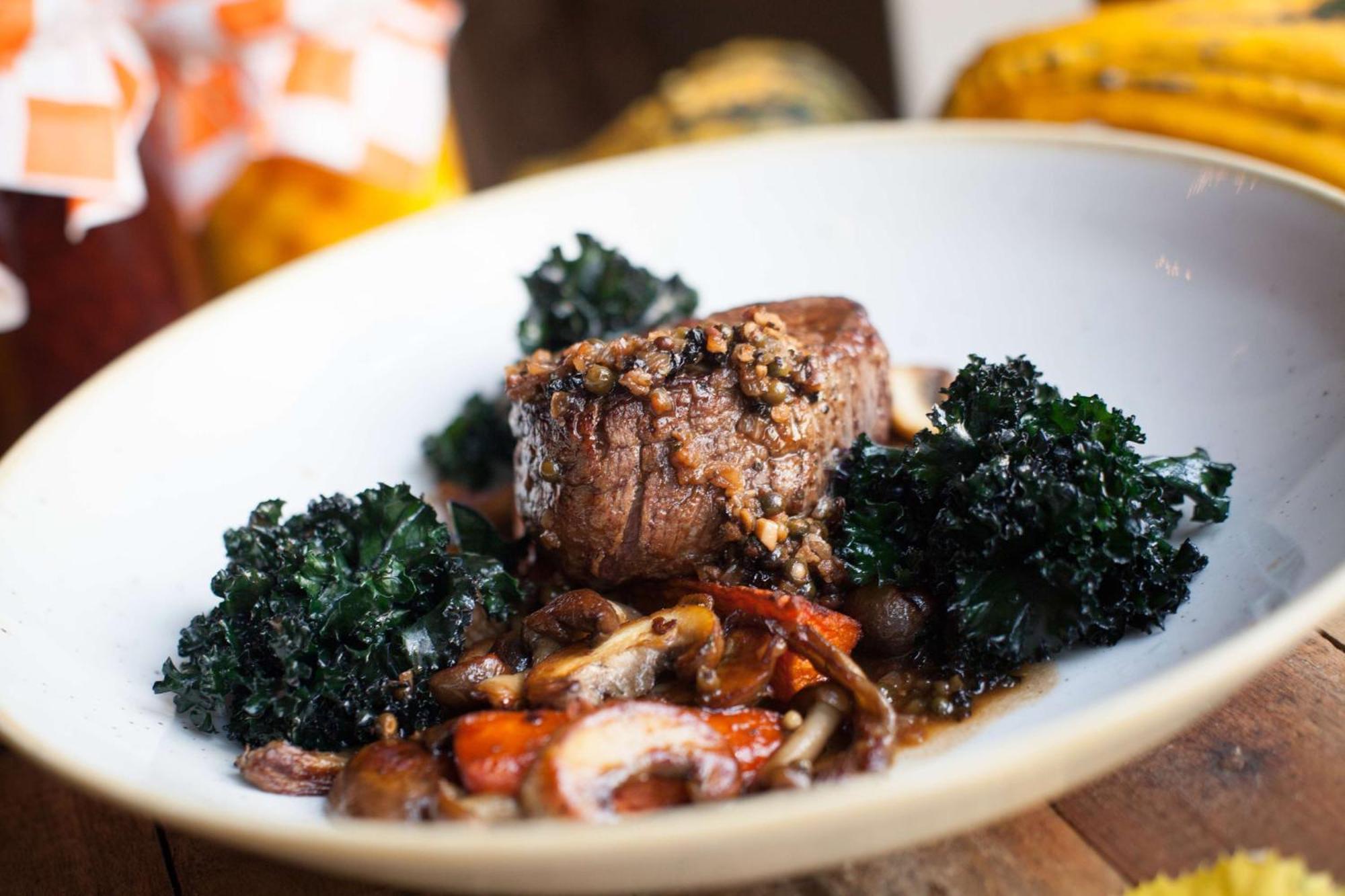 Radisson Blu Hotel, Danzica Esterno foto The photo showcases a beautifully plated dish featuring a piece of meat, likely a steak or roast, which is garnished with a crust or seasoning on top. Surrounding the meat are vibrant dark green kale leaves. The plate also includes a colorful assortm