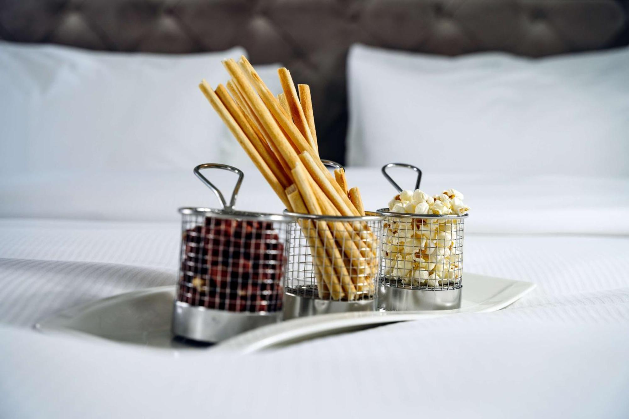 Radisson Blu Hotel, Danzica Esterno foto The photo shows a tray with three small metal baskets. Each basket contains a different type of snack. 

1. The first basket holds breadsticks, which are long and thin, arranged upright.
2. The second basket contains what appears to be chocolate-cove