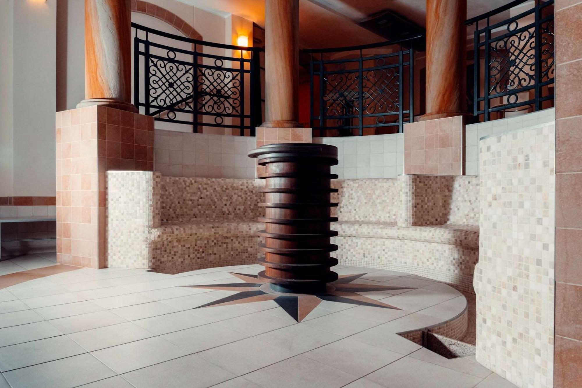 Radisson Blu Hotel, Danzica Esterno foto The photo showcases a well-designed interior space, likely part of a spa or wellness center. In the center, there is a circular seating area made of tiled blocks arranged in a semicircular pattern. The floor features a star-shaped design with contras