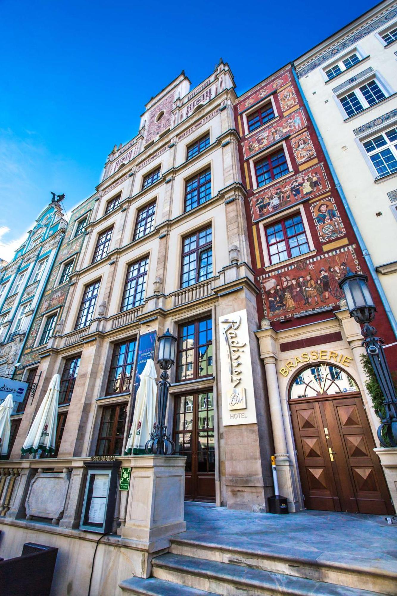 Radisson Blu Hotel, Danzica Esterno foto The photo shows a historic building with a richly decorated facade. The architecture features large windows and intricate details, including murals or painted scenes on the walls. There is a sign that indicates a brasserie, suggesting that this locat