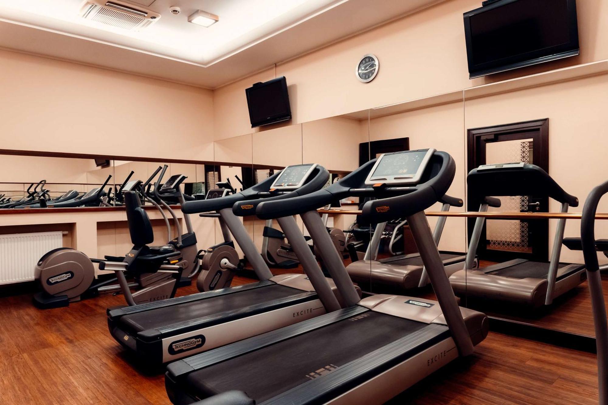 Radisson Blu Hotel, Danzica Esterno foto The photo shows a gym or fitness center with several exercise machines. There are multiple treadmills lined up in the foreground, each equipped with a display screen. In the background, there are additional fitness machines, including stationary bike