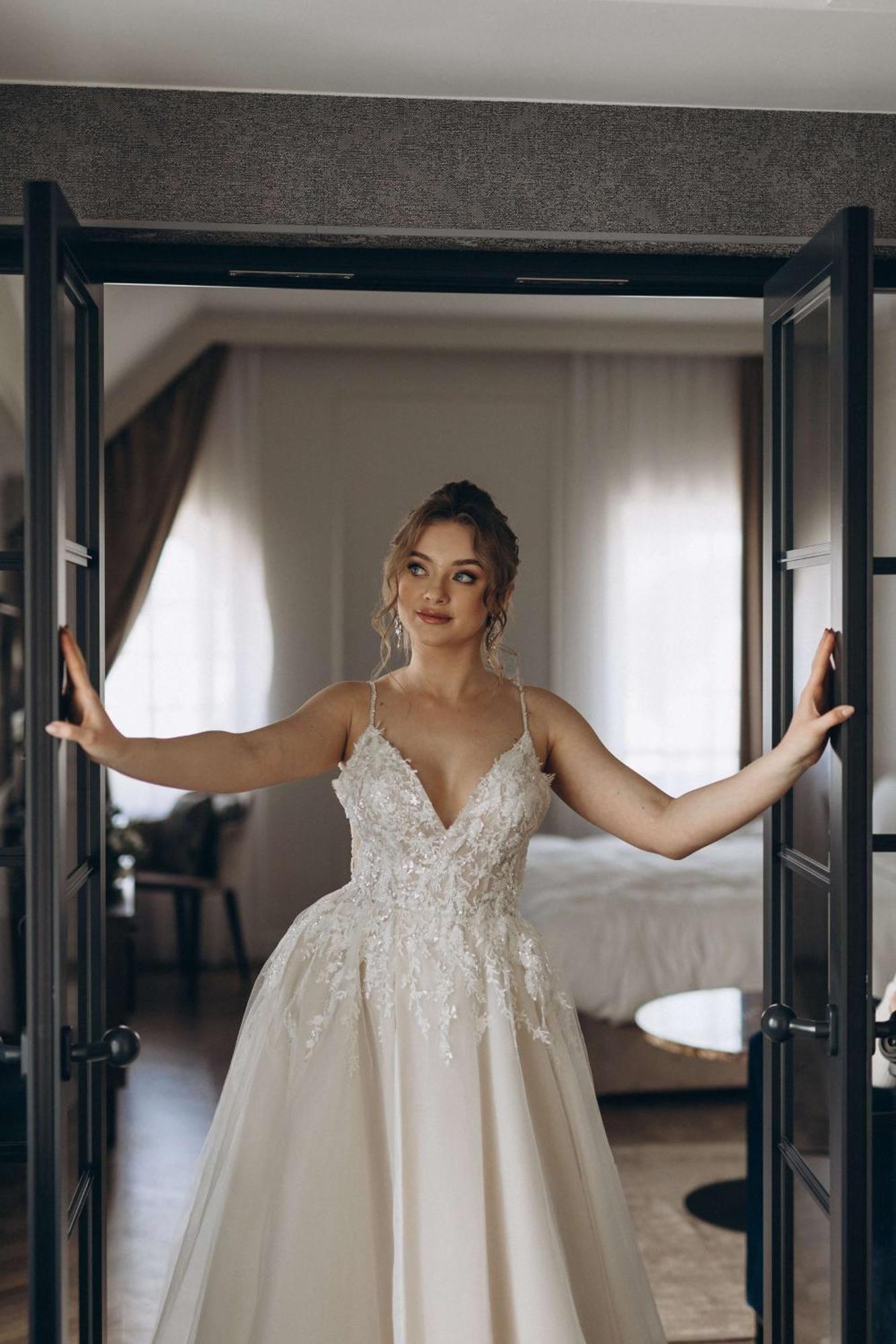 Radisson Blu Hotel, Danzica Esterno foto The photo shows a young woman standing between two open doors. She is wearing a beautiful wedding gown adorned with intricate details. Her hair is styled elegantly, and she has a thoughtful expression on her face. The setting appears to be a stylish 